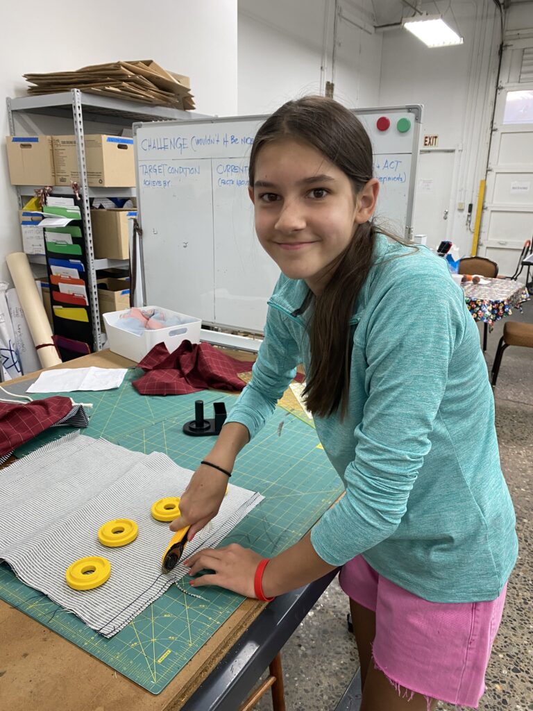 Girl cutting fabric for school supply kit backpacks